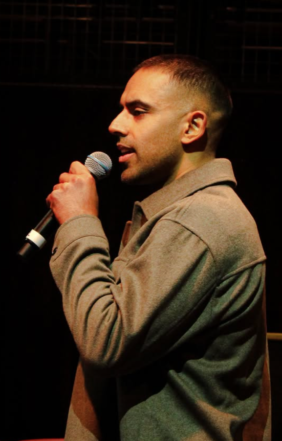 Dr Sandhu speaking on stage with a microphone